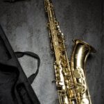 brass saxophone on gray table near black bag