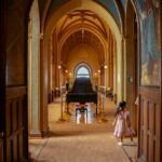 a little girl in a dress standing in the hallway of a castle